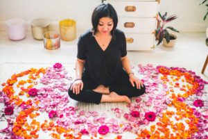 Anjie Cho sitting the floor with flower pedals surrounding her - Feng Shui